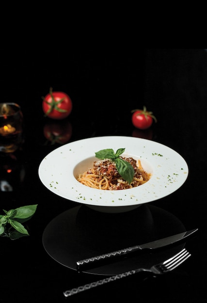 Een bord spaghetti in een donker restaurant.