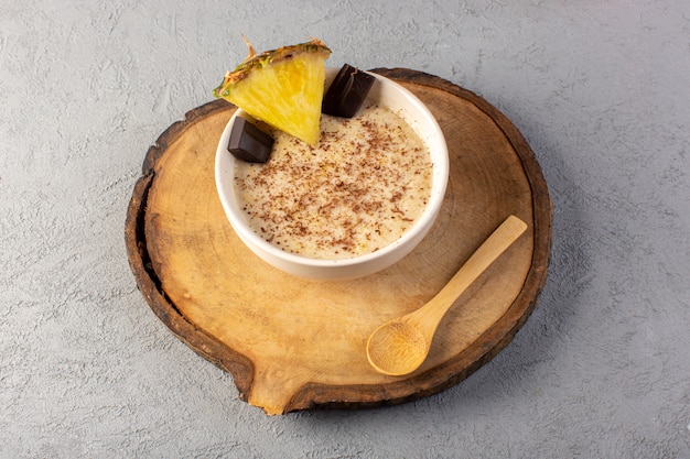 Een bovenaanzicht choco dessert bruin met ananas segment choco bars op het bruine houten bureau en grijs