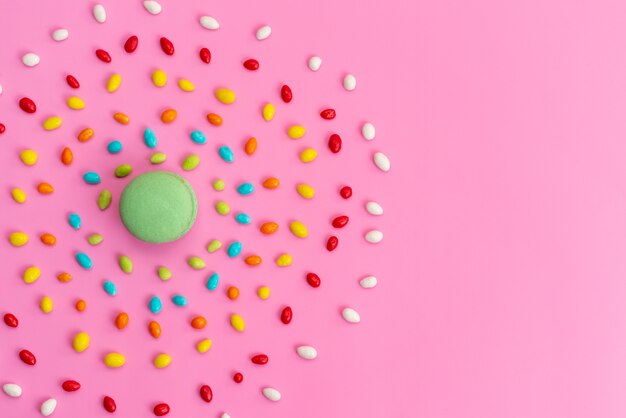 Een bovenaanzicht Franse macarons met kleurrijke snoepjes op roze, suiker cake biscuit kleur samenstelling regenboog