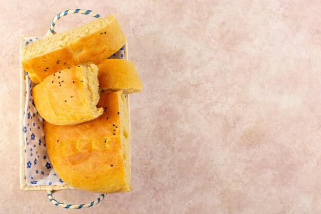 Een bovenaanzicht gebakken brood warm lekker vers gesneden in broodtrommel op roze