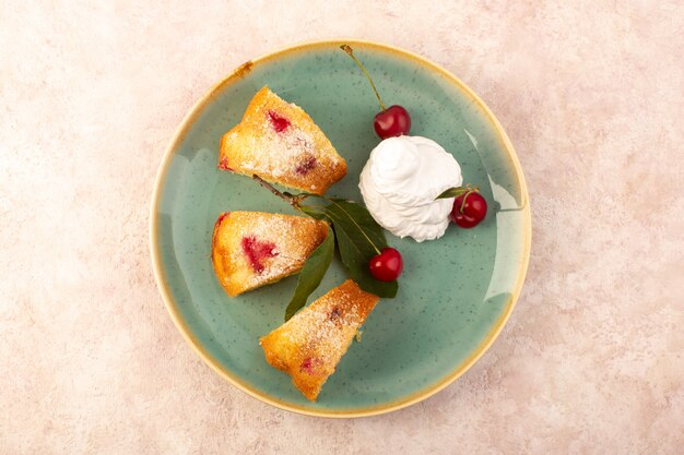 Een bovenaanzicht gebakken fruitcake heerlijk gesneden met rode kersen binnen en suikerpoeder binnen ronde groene plaat op roze