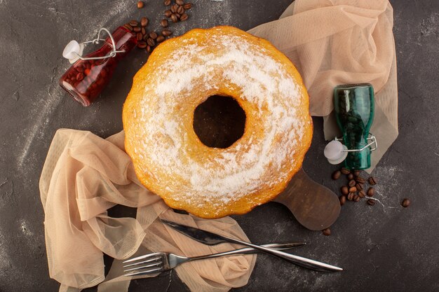 Een bovenaanzicht gebakken ronde cake met suikerpoeder en koffiezaden op het houten bureau
