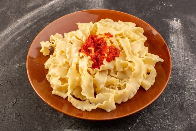 Een bovenaanzicht gekookte Italiaanse pasta met tomatensaus in plaat