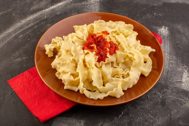 Een bovenaanzicht gekookte Italiaanse pasta met tomatensaus in plaat