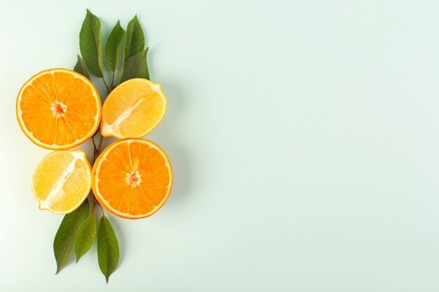 Een bovenaanzicht gesneden sinaasappel, vers, rijp, sappig, zacht, geïsoleerd, half gesneden stukjes, samen met gesneden citroenen en groene bladeren op de ijsblauwe achtergrond, fruitkleur, citrus