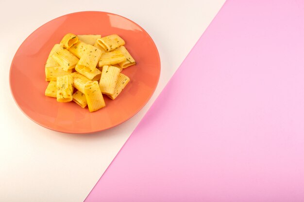 Een bovenaanzicht Italiaanse pasta met gedroogde groene kruiden in roze plaat op wit-roze