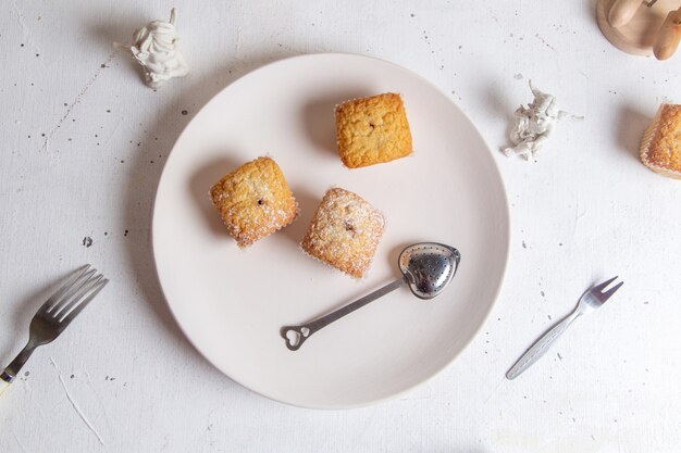 Een bovenaanzicht kleine cakes gebakken en lekker in papier vormen op het witte oppervlak