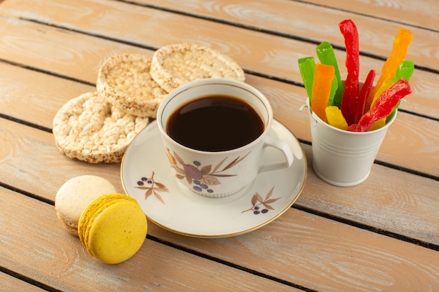 Een bovenaanzicht kopje koffie warm en sterk met Franse macarons en marmelade op de crèmekleurige rustieke tafel drink koffie foto koekje