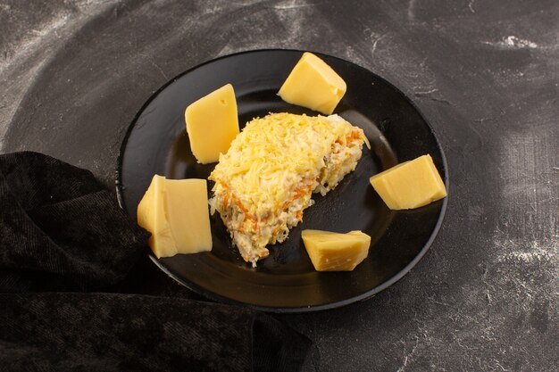 Een bovenaanzicht mayyonaised groentesalade met verse kaas in zwarte plaat op de grijze maaltijd van het bureausalade