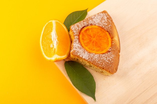 Een bovenaanzicht oranje cake segment zoete heerlijke smakelijke stuk op de crème gekleurde houten bureau en gele achtergrond zoete suiker koekje