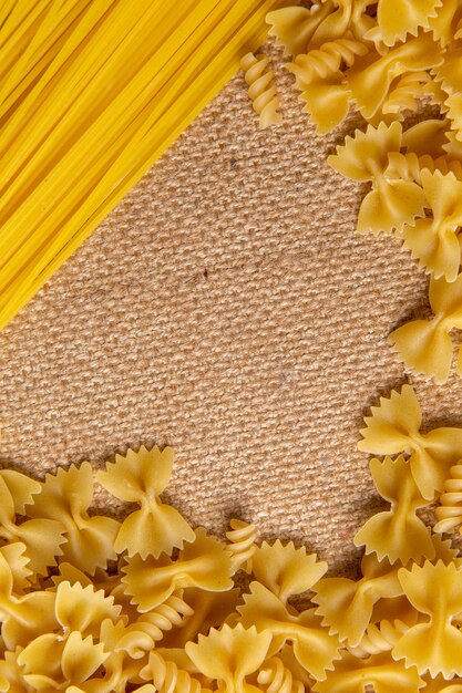 Een bovenaanzicht rauwe Italiaanse pasta klein en lang gevormd verspreid over de bruine zak pasta Italiaans eten maaltijd