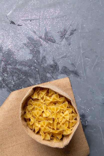 Een bovenaanzicht rauwe Italiaanse pasta weinig gevormd in zak op de grijze bureau pasta Italiaans eten maaltijd