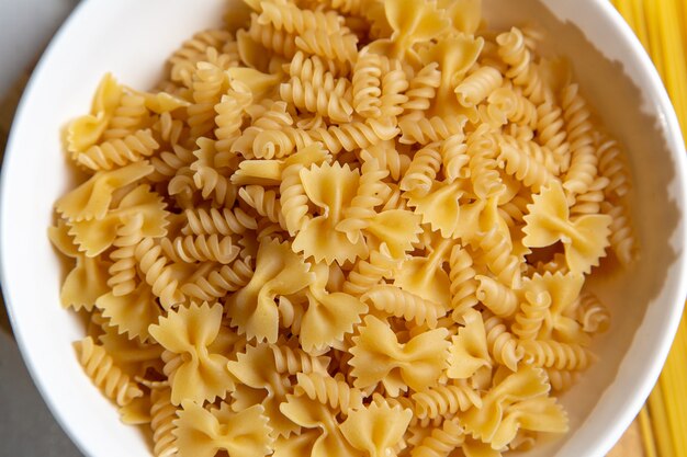 Een bovenaanzicht rauwe Italiaanse pasta weinig gevormd op de houten bureau pasta Italiaans eten maaltijd