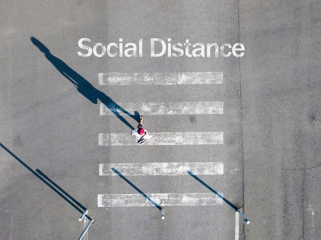 Een bovenaanzicht, tekst voor sociale afstand op het asfalt, persoonsstop op de grond, concept van coronaviruspandemie