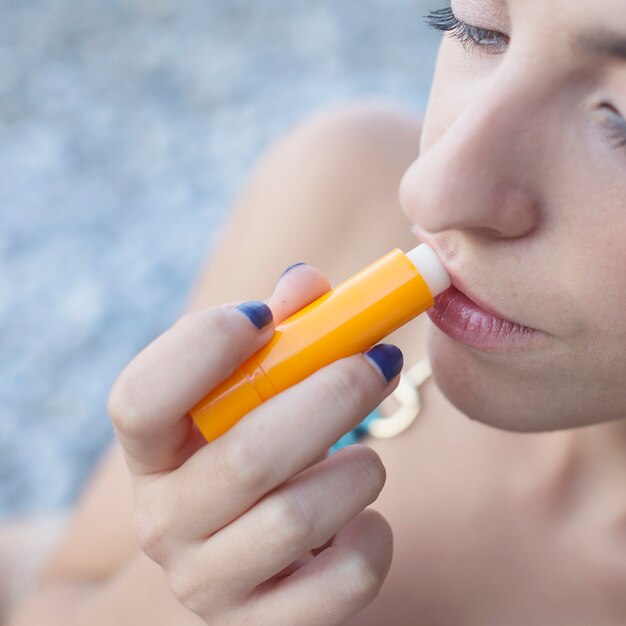 Een bovenaanzicht van een jonge vrouw die lippenbalsem toepast