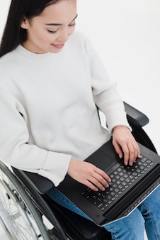 Een bovenaanzicht van een jonge vrouw zittend op een rolstoel met behulp van laptop