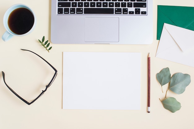 Een bovenaanzicht van een laptop met briefpapier en kopje thee op gekleurde achtergrond