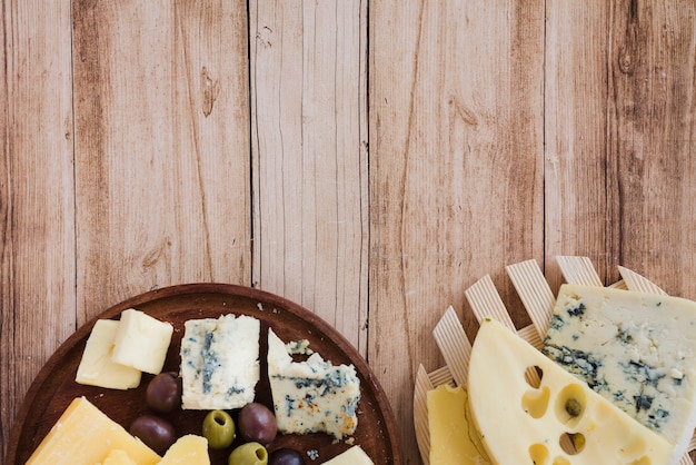 Een bovenaanzicht van emmental; gouda en blauwe kaas op coaster en snijplank