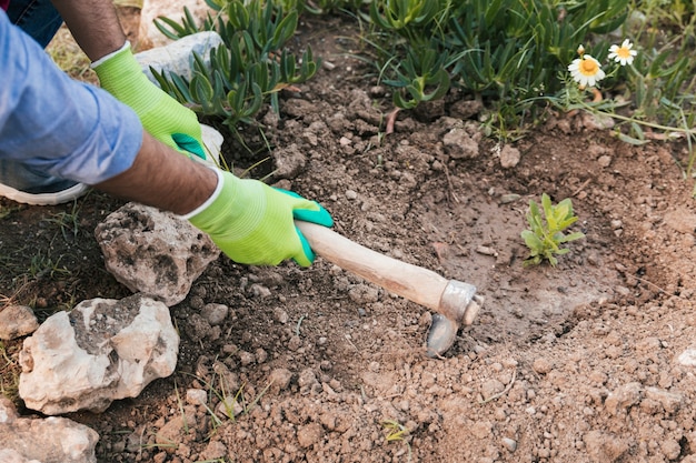 Een bovenaanzicht van iemands hand graven van de bodem met schoffel