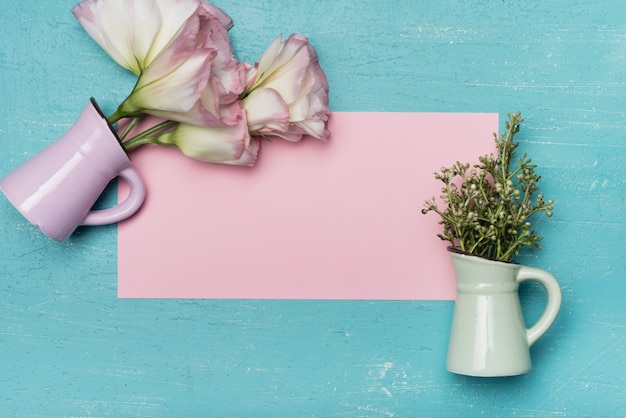 Gratis foto een bovenaanzicht van keramische vazen ​​op roze blanco papier op houten blauwe achtergrond