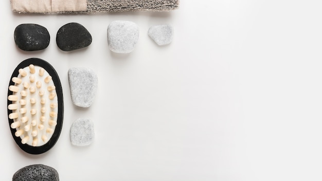 Een bovenaanzicht van massageborstel; spa steen en puimsteen op witte achtergrond
