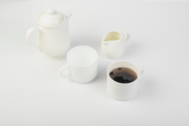 Een bovenaanzicht van melk; thee en theepot op witte achtergrond