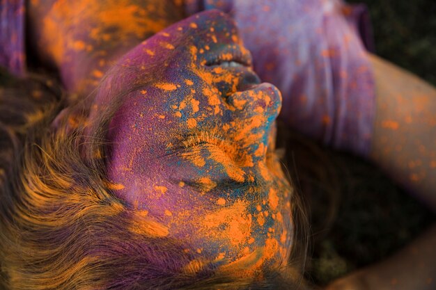 Een bovenaanzicht van oranje holi kleur poeder op het gezicht van de vrouw