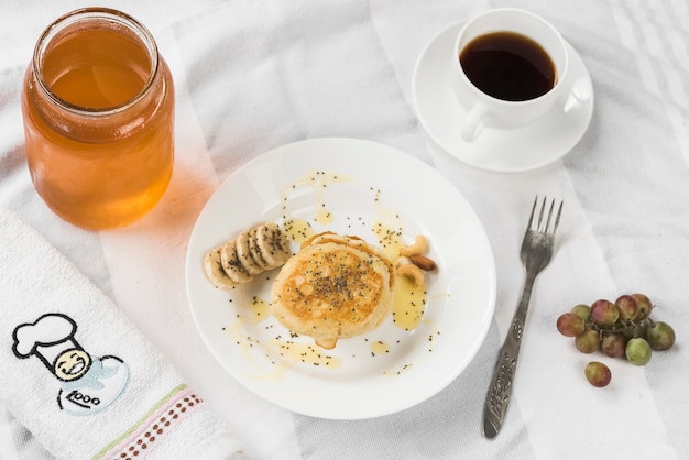 Een bovenaanzicht van pannenkoek met honing; banaanplakken en chiazaden op plaat