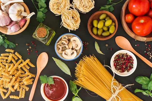 Gratis foto een bovenaanzicht van rauwe pasta met ingrediënten op zwarte achtergrond