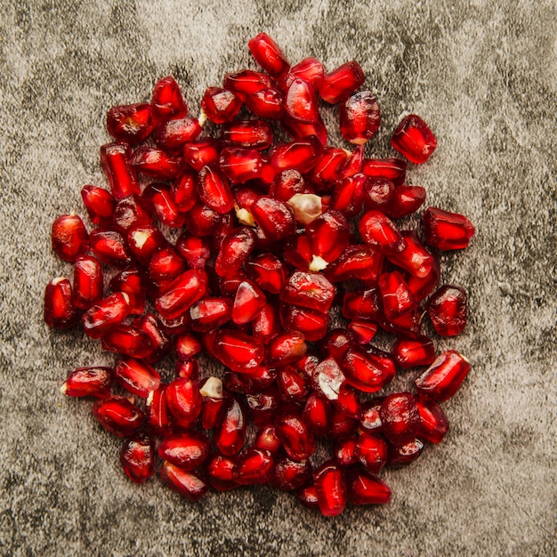 Gratis foto een bovenaanzicht van rode granaatappelzaden op grungeachtergrond