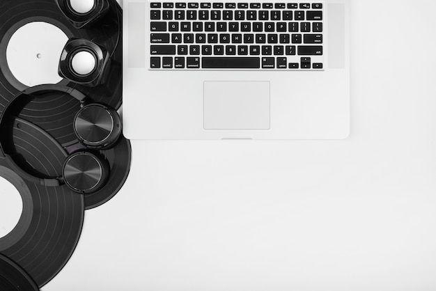 Een bovenaanzicht van vinylplaten; hoofdtelefoon en draadloze luidspreker met laptop