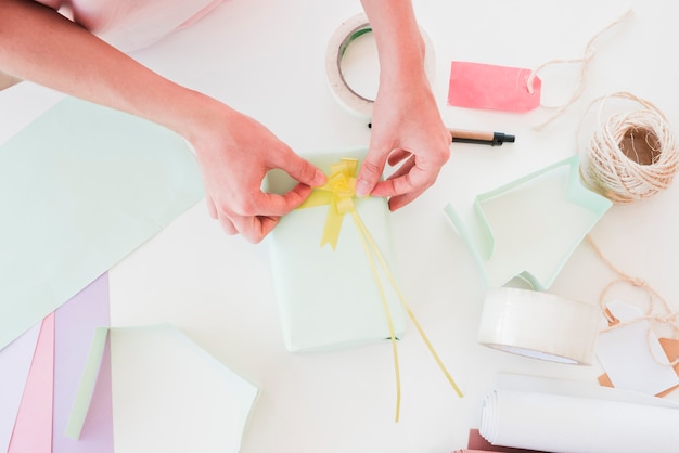 Een bovenaanzicht van vrouw steken gele lint op gewikkeld geschenk doos