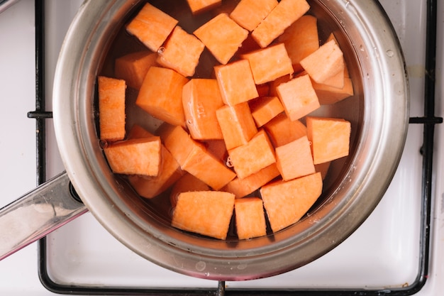 Een bovenaanzicht van zoete aardappelen plak koken in de metalen pan op gas