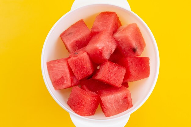 Een bovenaanzicht vers gesneden watermeloen in witte, plastic plaat op geel, fruit kleur zomer