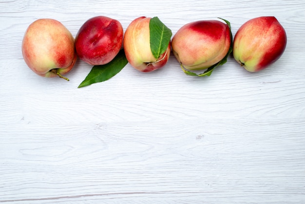 Een bovenaanzicht verse perziken zuur en zacht op de witte achtergrond fruit kleur vers