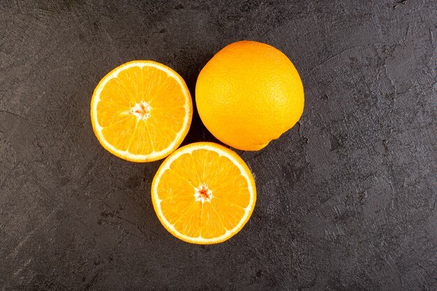 Een bovenaanzicht verse sinaasappelen zure rijp geheel en gesneden mellow citrus tropische vitamine geel op het donkere bureau