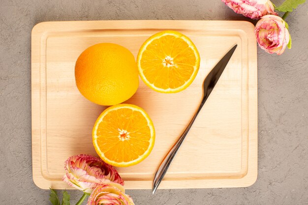 Een bovenaanzicht verse sinaasappelen zure rijp gesneden en hele zachte citrus sappige tropische vitamine geel op de crème bureau