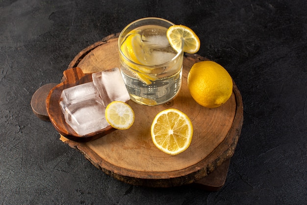 Een bovenaanzicht water met verse frisse citroen drankje in glas met ijsblokjes met gesneden citroenen op de donkere achtergrond cocktail drinken fruit