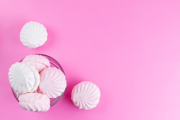 Een bovenaanzicht witte schuimgebakjes in ronde glazen kom op roze