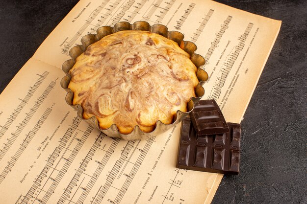 Een bovenaanzicht zoete ronde cake lekker heerlijk binnen taartvorm samen met choco bars op de grijze achtergrond koekje suiker koekje