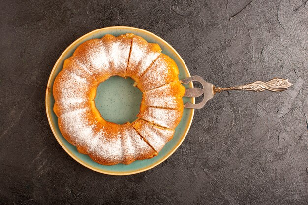 Een bovenaanzicht zoete ronde cake met suiker poeder op de top gesneden zoete heerlijke geïsoleerde binnen plaat en grijze achtergrond koekje suiker koekje