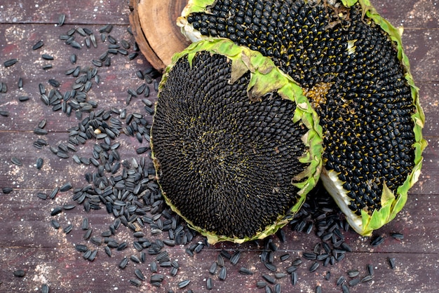 Een bovenaanzicht zwarte zonnebloempitten vers en smakelijk veel op het bruine bureau graan zonnebloempitten snackolie