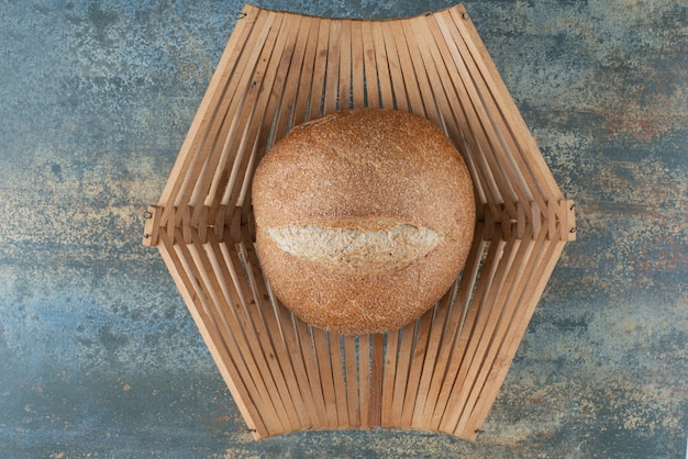 Een broodje vers bruin brood op houten mand