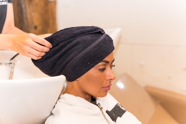 Een brunette vrouw zit in de schoonheidssalon haar haar te drogen