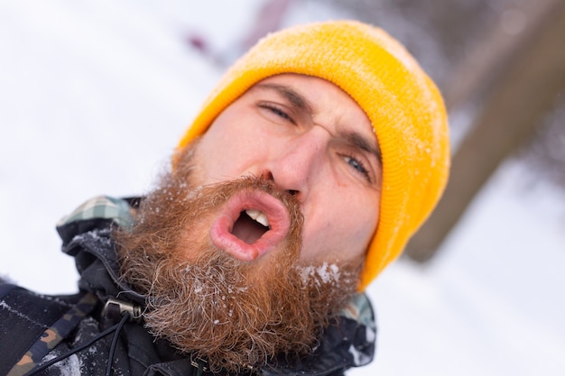 Een close portret van een man met een baard, allemaal gezicht in de sneeuw, in een besneeuwd bos