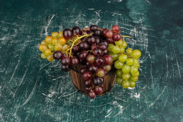 Een cluster van groene en zwarte druiven op marmeren tafel.