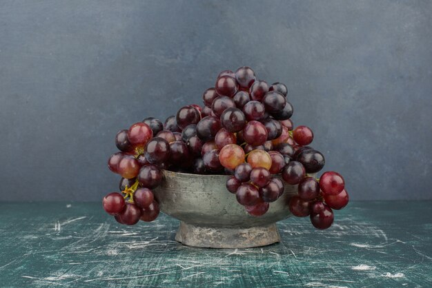 Een cluster van zwarte druiven in de vaas op marmeren tafel.