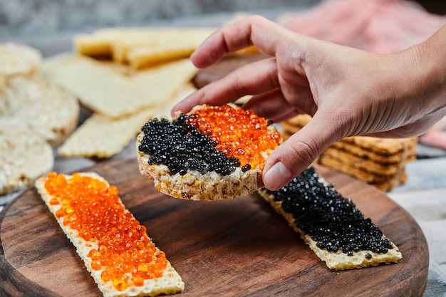 Een cracker-sandwich nemen met rode en zwarte kaviaar.