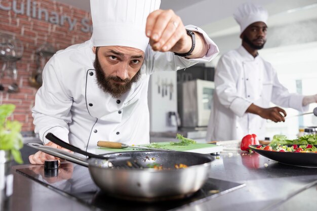 Een culinaire expert in een commerciële keuken bereidt een gerecht met verse basilicum en peterselie
