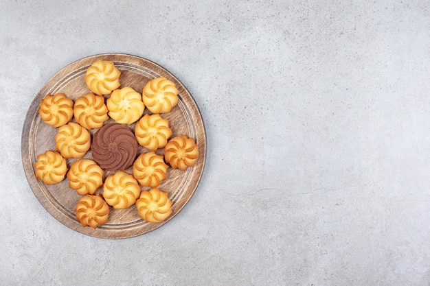 Een decoratief arrangement van hartige koekjes op een houten bord op marmeren achtergrond.